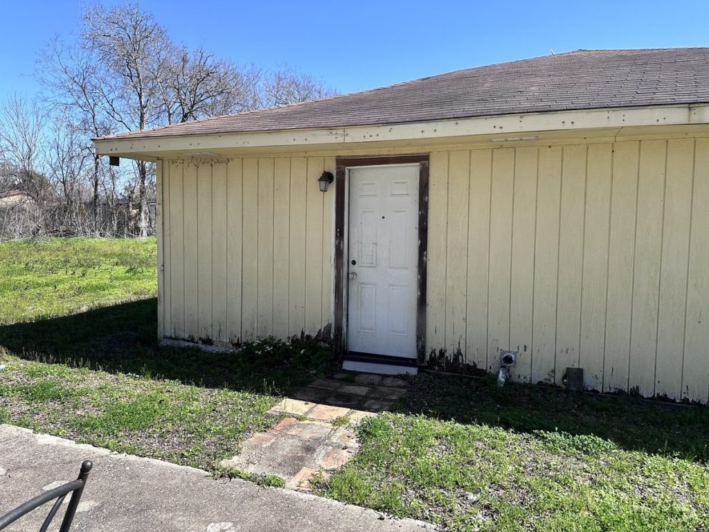 Weathered rear entrance of vacant inherited house in Sunrise Courts, Baytown TX