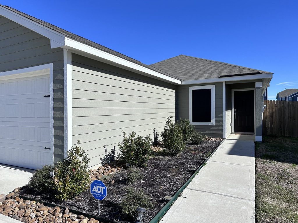 Side exterior and entryway of new-construction home purchased by cash home buyers in Mont Belvieu, TX