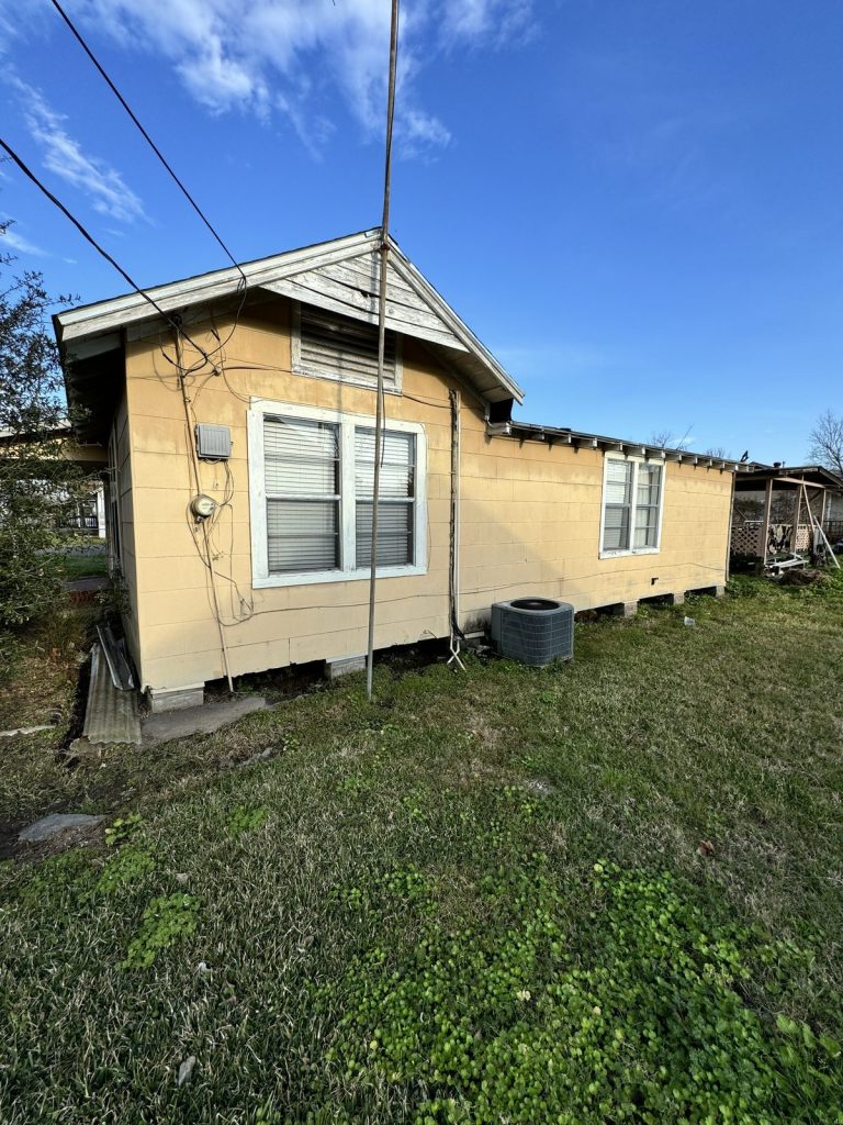 Side view of pier-and-beam home with aging siding purchased as-is by cash home buyers in Baytown TX