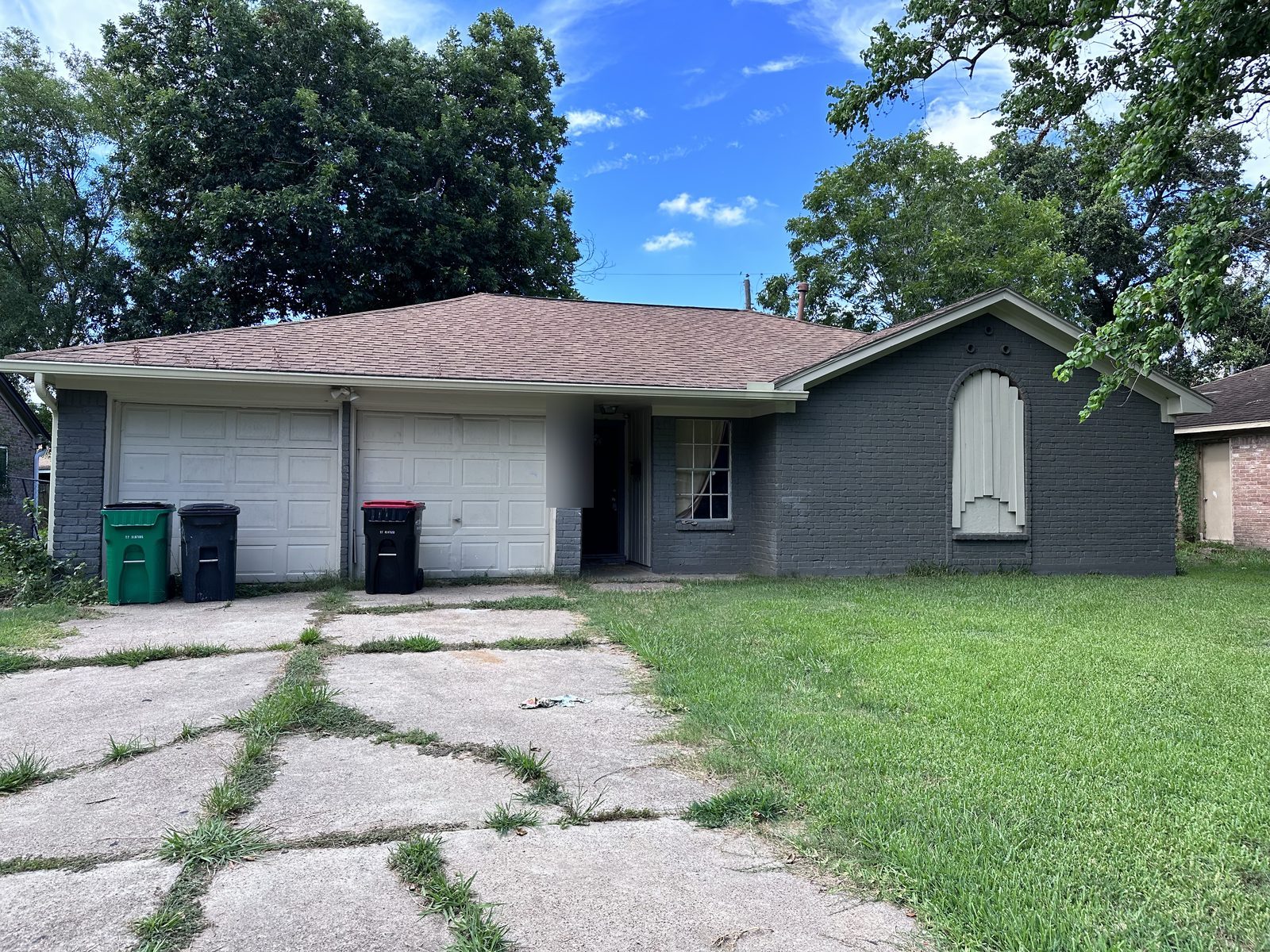 Front of abandoned inherited brick home with boarded window bought for cash as-is in Baytown TX