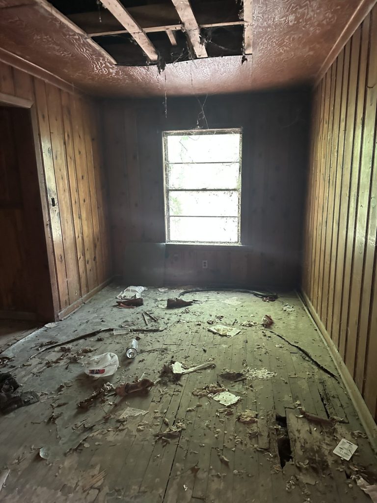 Bedroom with fallen ceiling and damaged floor in abandoned Baytown TX house bought as-is