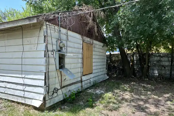 Side view of vandalized Lake Park Drive property with boarded windows and deferred maintenance