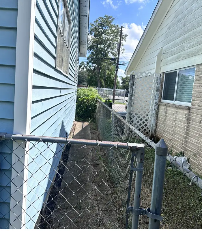 Side yard of a Rosenberg property showing deferred maintenance and repair concerns