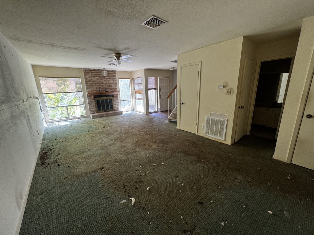 Brick fireplace in a vacant living area at a Grogan's Mill townhome sold for cash