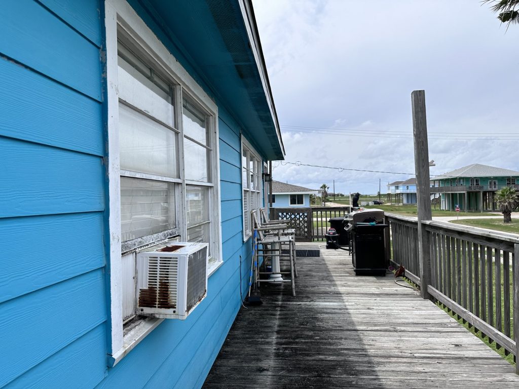 Weathered decking and rusted window unit on as-is beach house bought in Freeport TX