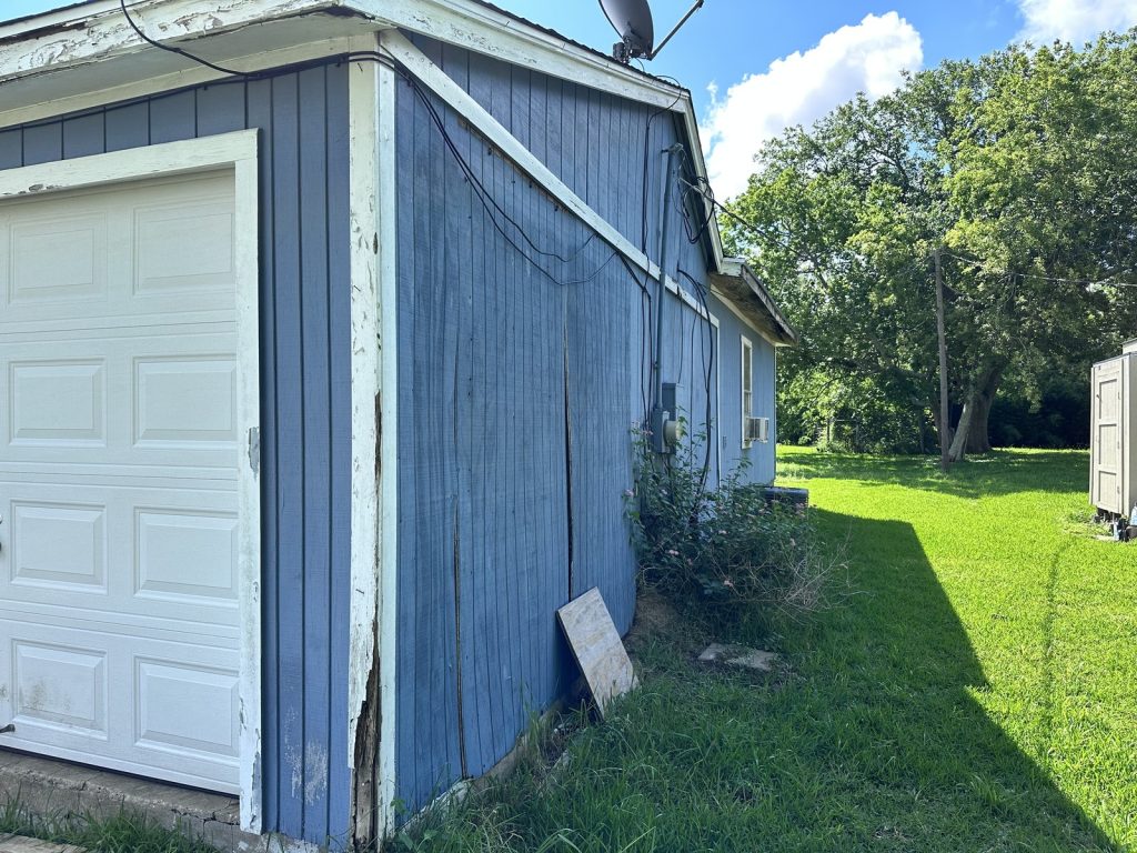 Weathered board-and-batten siding on as-is home purchased in Freeport TX