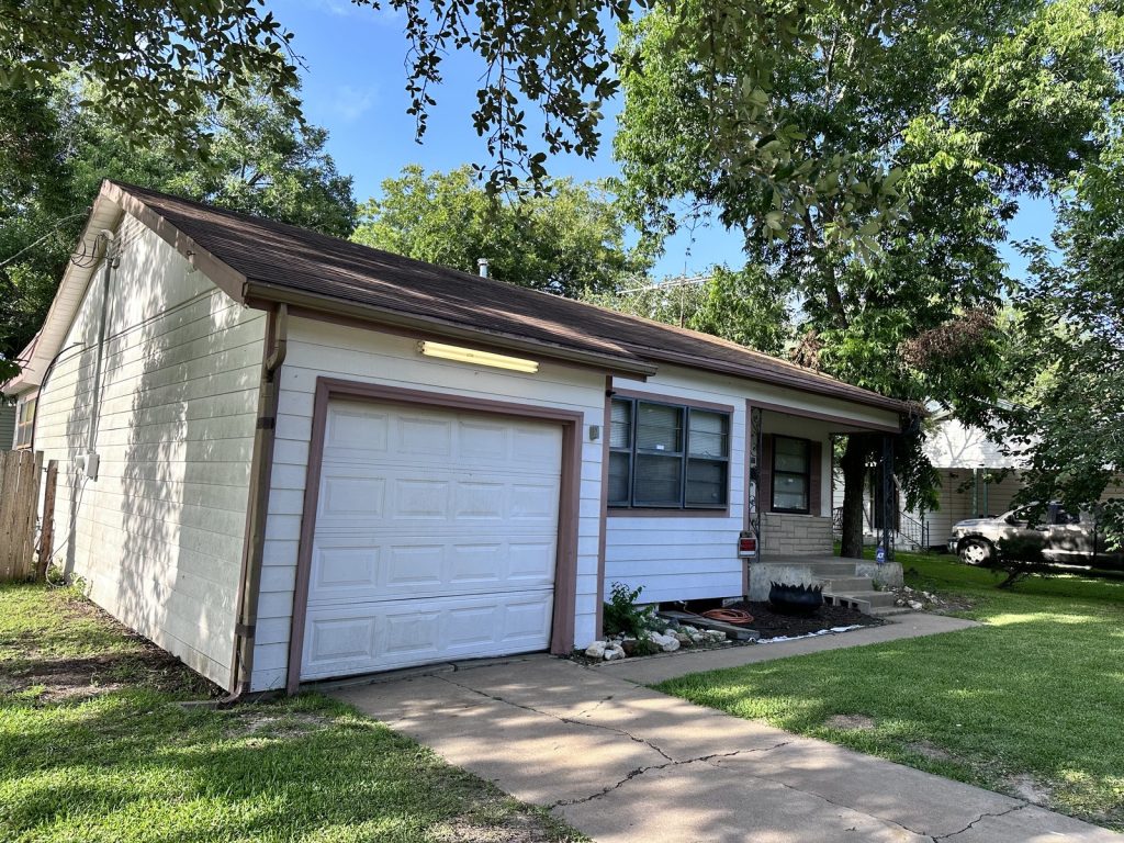 Attached garage and driveway of as-is rental home purchased in La Marque TX