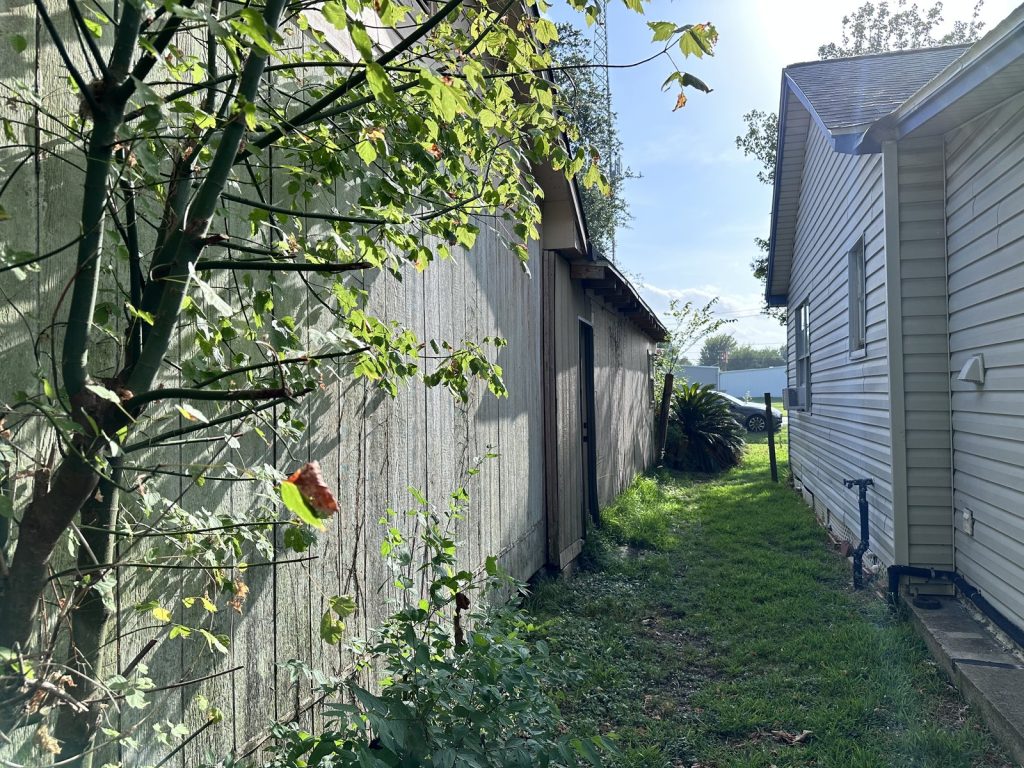 Weathered outbuilding beside main house at as-is property bought in La Porte TX