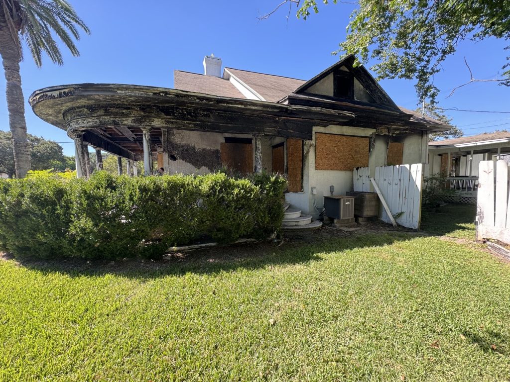Fire-damaged front porch and boarded windows of as-is home bought for cash by Volcan Property Buyers in Texas City TX purchased quickly by volcan property buyers