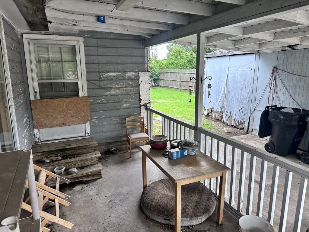 Worn back porch with peeling paint on as-is home sold for cash in southeast Houston TX