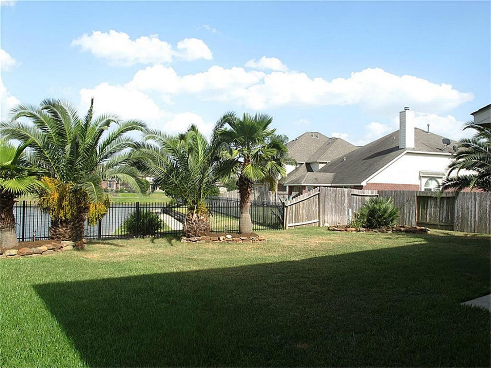 Backyard with palm trees and water view at a Bridgestone rental home in Spring, TX purchased for cash