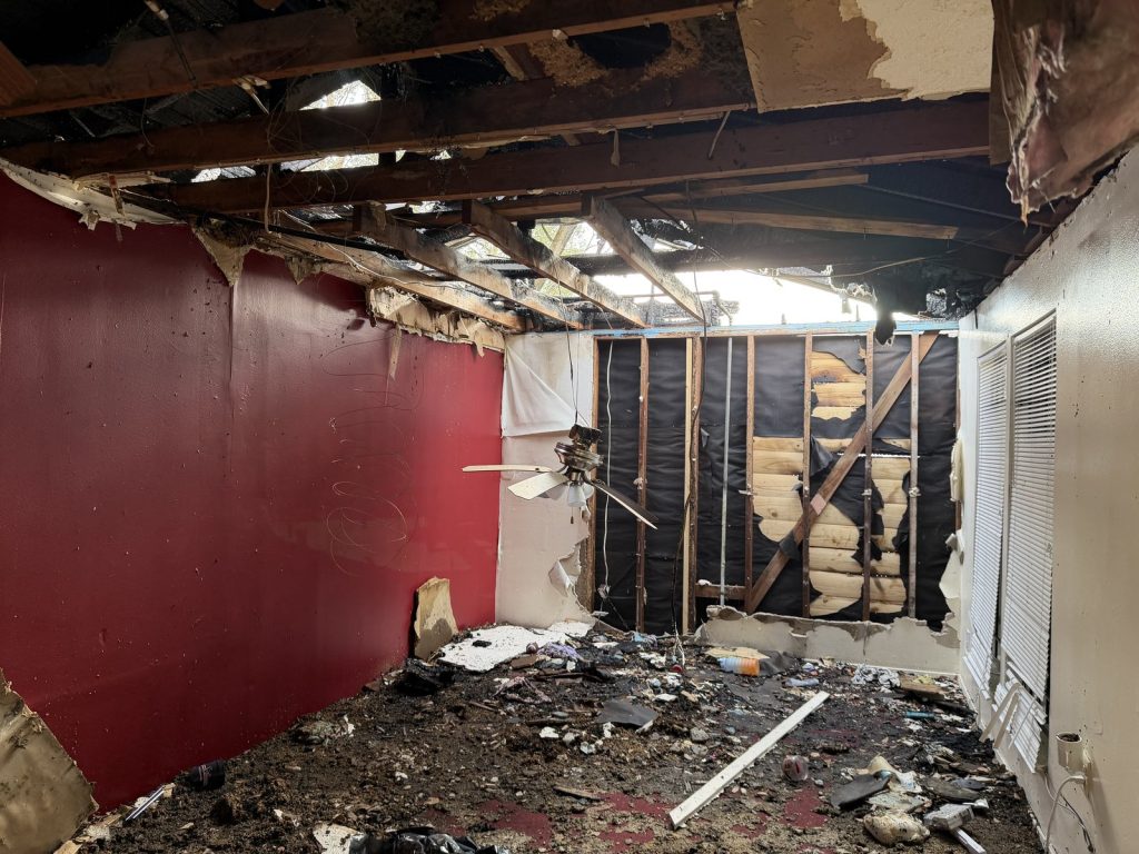 Interior fire damage with collapsed ceiling and exposed framing in a Northeast Houston home sold for cash