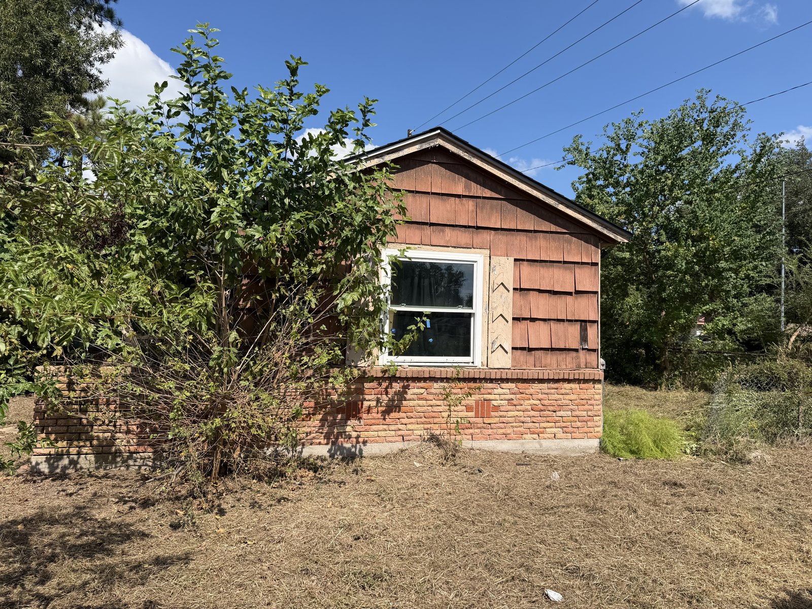 Wood shingle and brick exterior of an inherited home in Northwood Manor, Houston TX bought for cash
