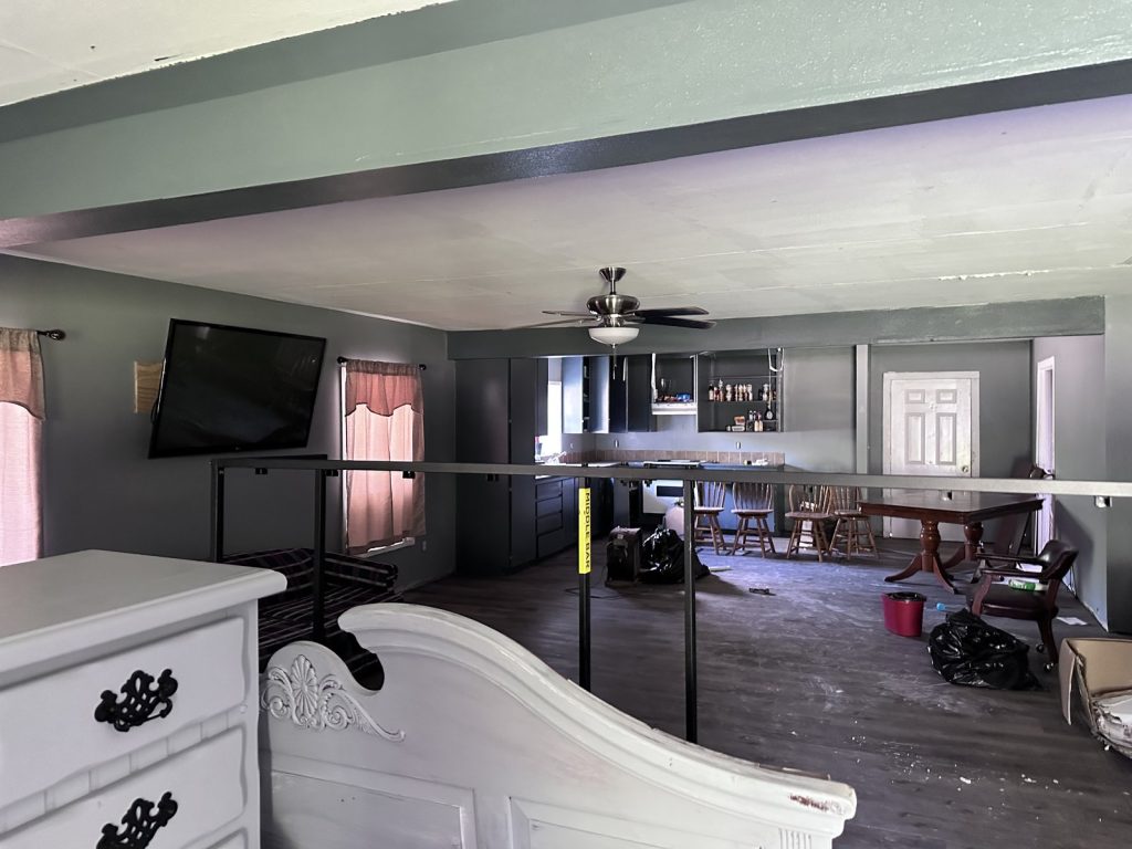 Cluttered living/dining room in a distressed rural property sold for cash in Cleveland, TX