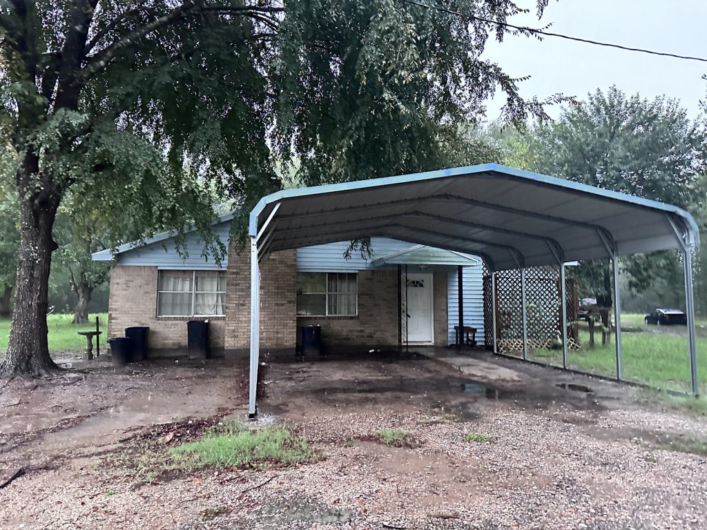 Carport and front exterior of a vacant 7-acre property sold for cash in Cleveland, TX