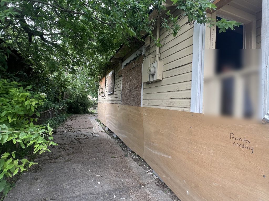 Boarded windows on a distressed vacant home sold for cash in Independence Heights, Houston, TX