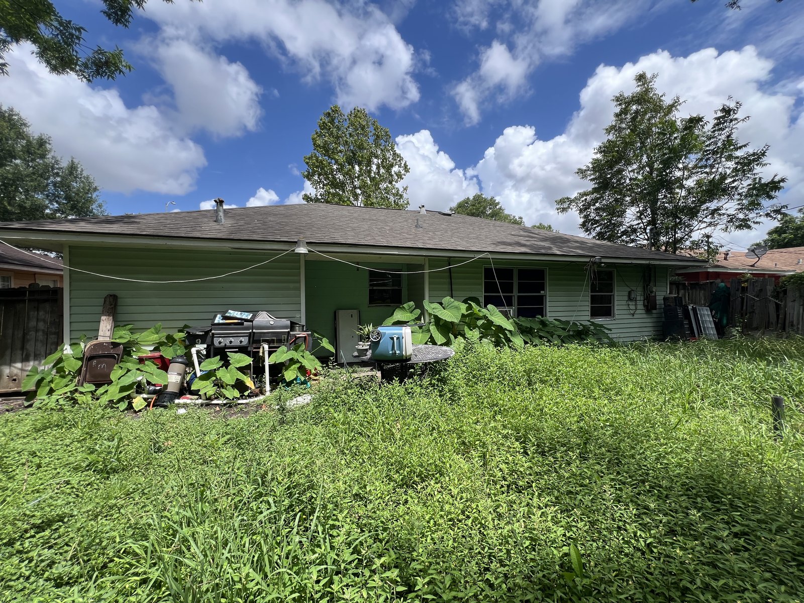 Rear exterior and overgrown yard of as-is home bought for cash in Oak Meadows, Houston TX