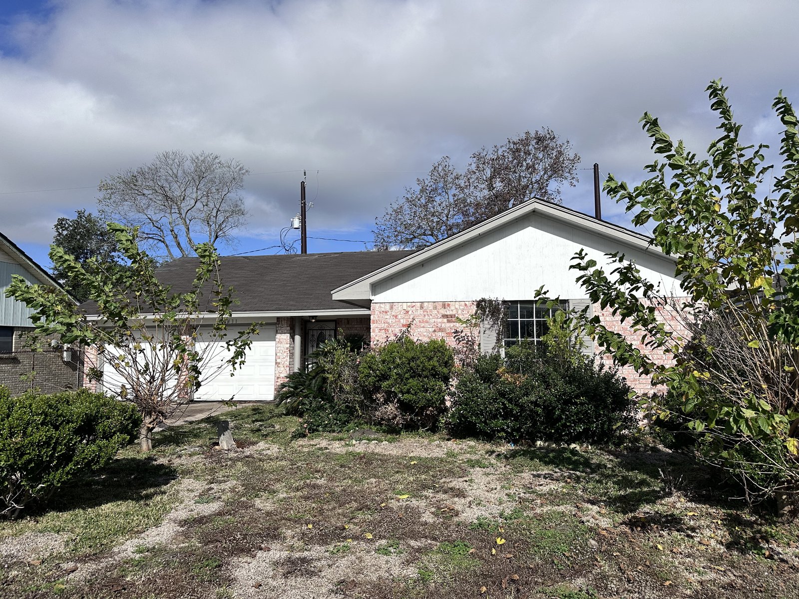 Front exterior of an inherited Quail Valley East home in Missouri City, TX with an overgrown yard