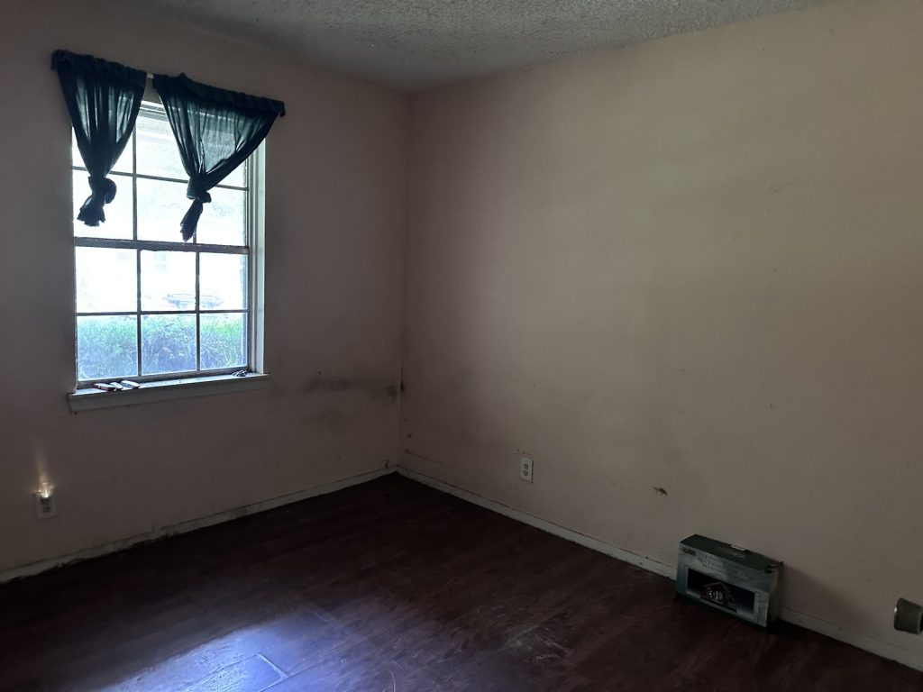 Water-damaged bedroom wall inside a flood-affected Northwood Manor, Houston home purchased as-is