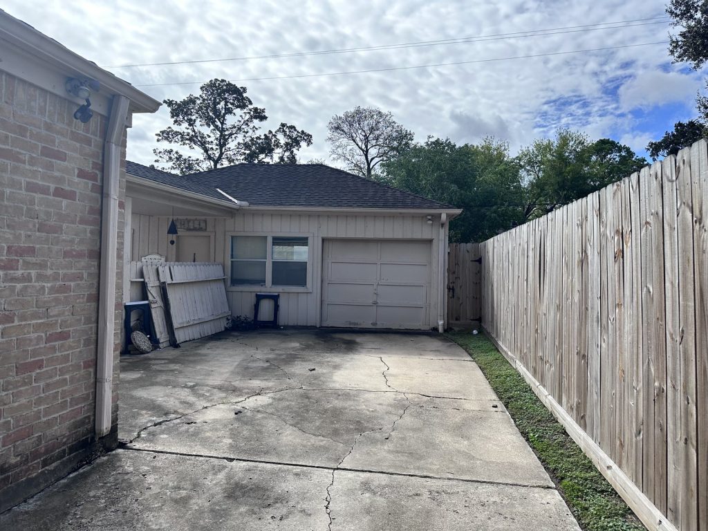 Rear garage and down fence panels at a west Houston TX house bought by cash home buyers