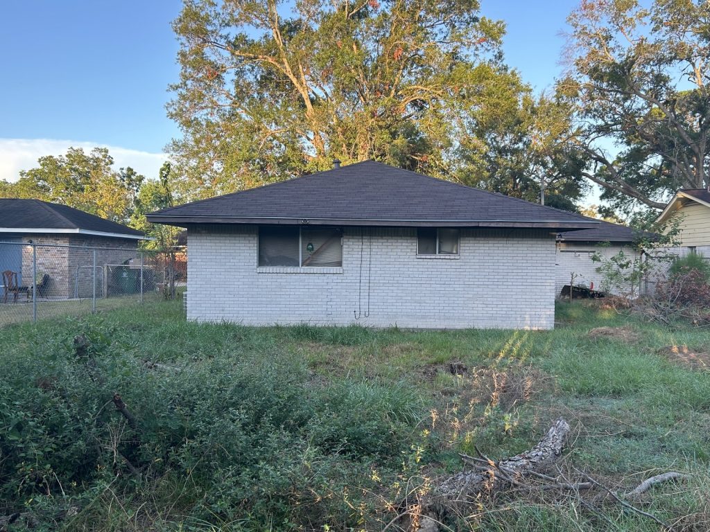 Side exterior of an abandoned, termite-damaged home sold for cash in Willow Run, Houston, TX