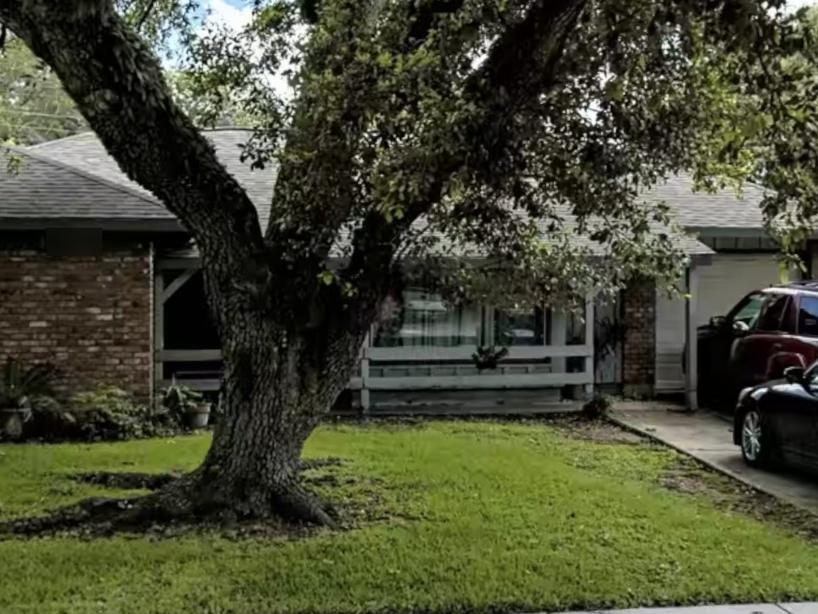 Front of brick rental home under a live oak bought for cash in Sharpstown, Houston TX