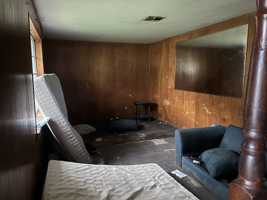 Disheveled bedroom inside a vacant Hempstead, TX home sold as-is
