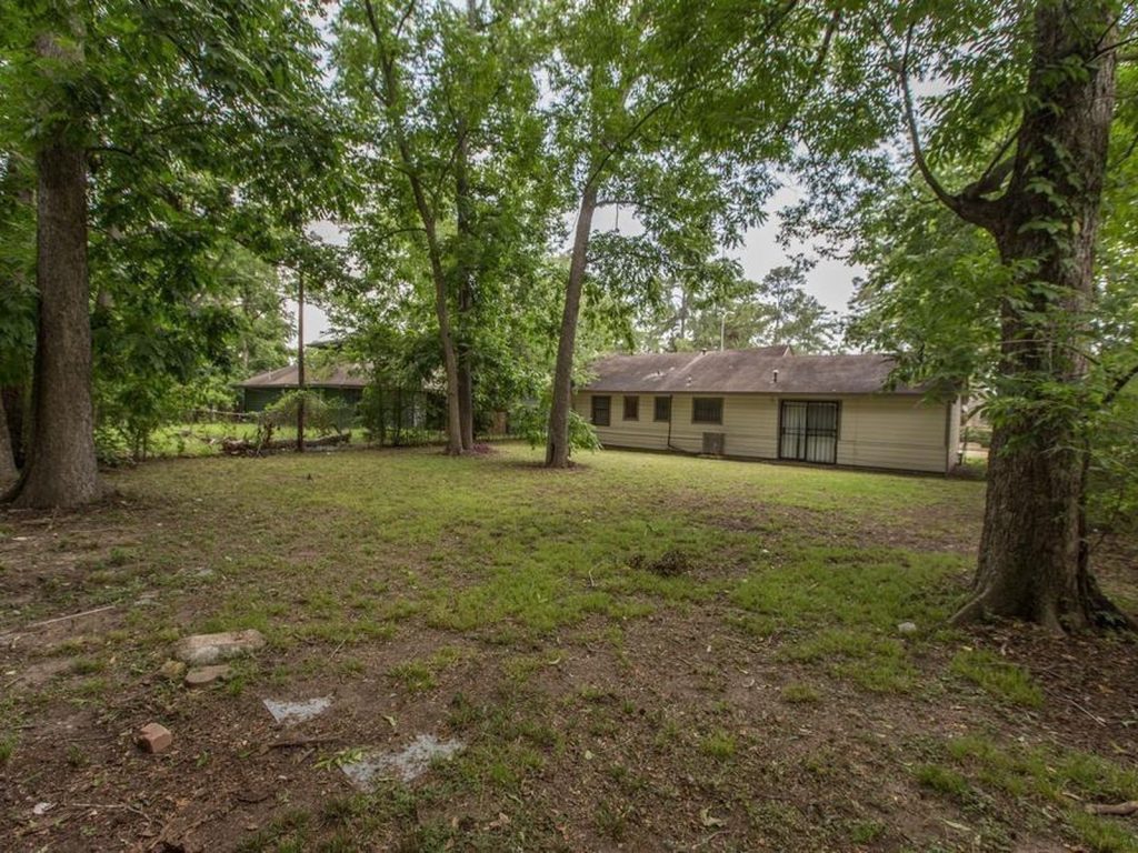 Wooded rear yard of an abandoned East Little York, Houston property purchased for cash