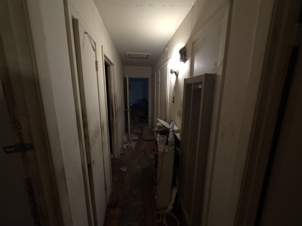 Damaged interior hallway with debris in Houston TX house sold as-is for cash