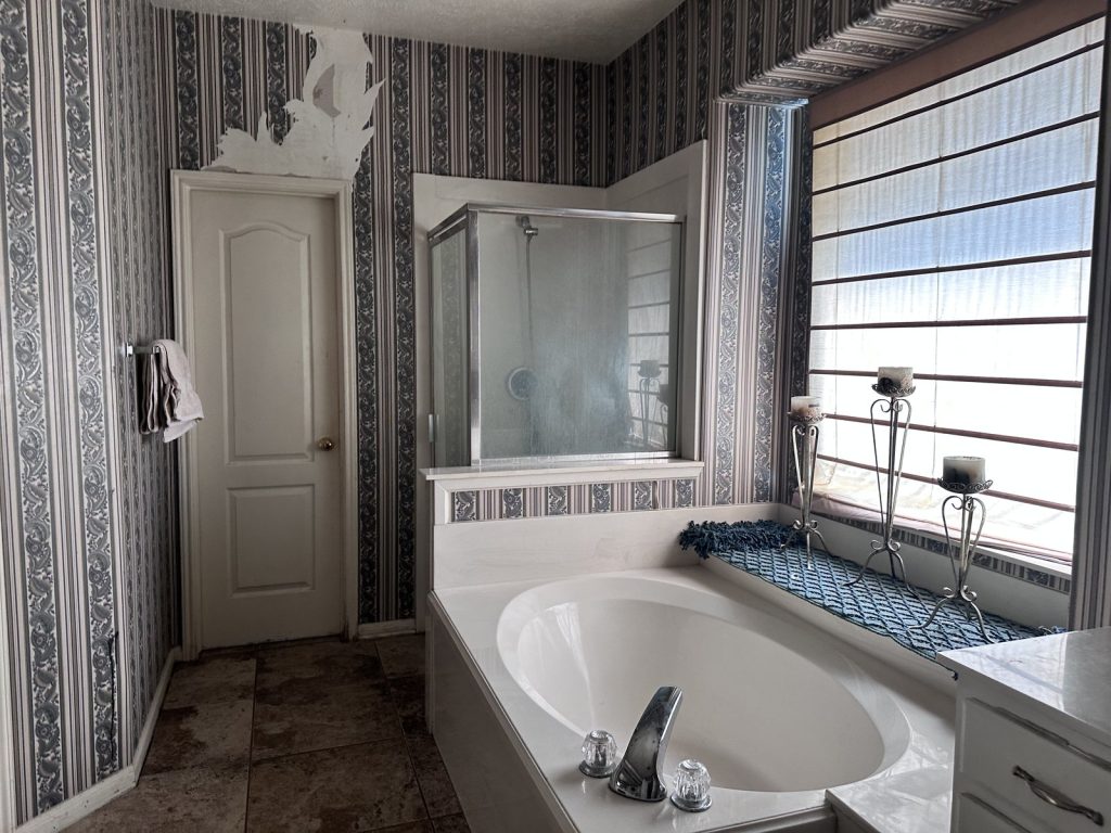 Water-damaged bathroom wallpaper at a Stafford, TX home purchased for cash
