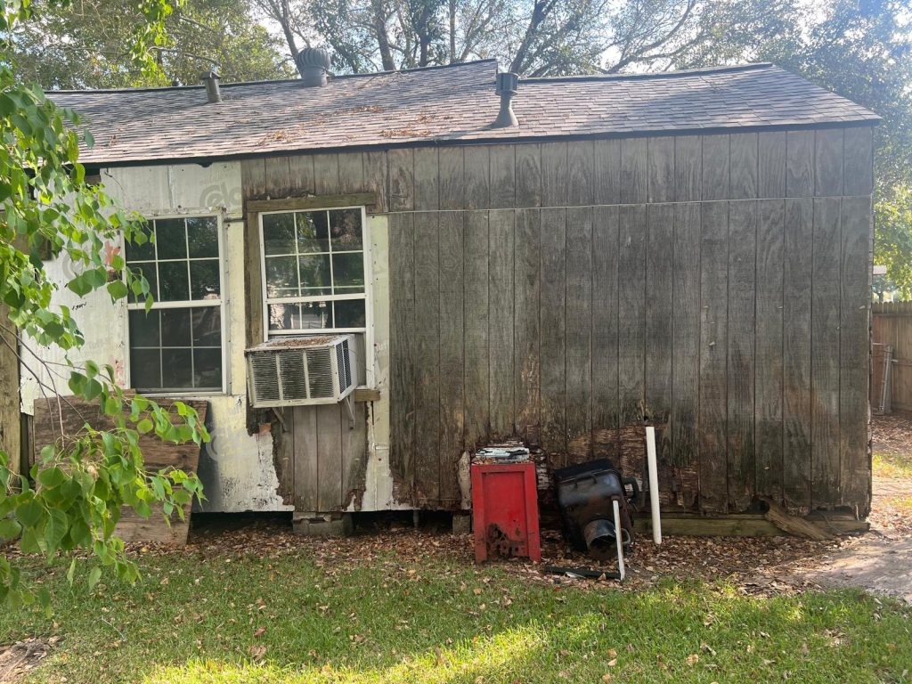 Deteriorated wood siding and exposed framing on as-is Baytown TX home sold to Volcan Property Buyers