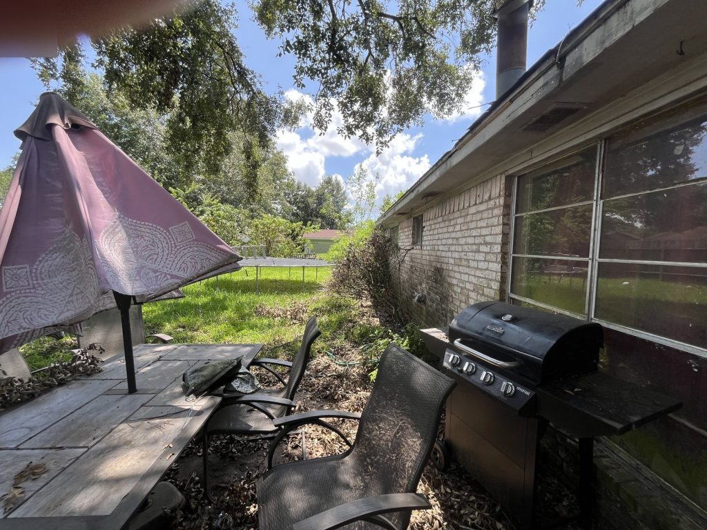 Covered patio and overgrown yard of inherited home purchased as-is in Deer Park TX