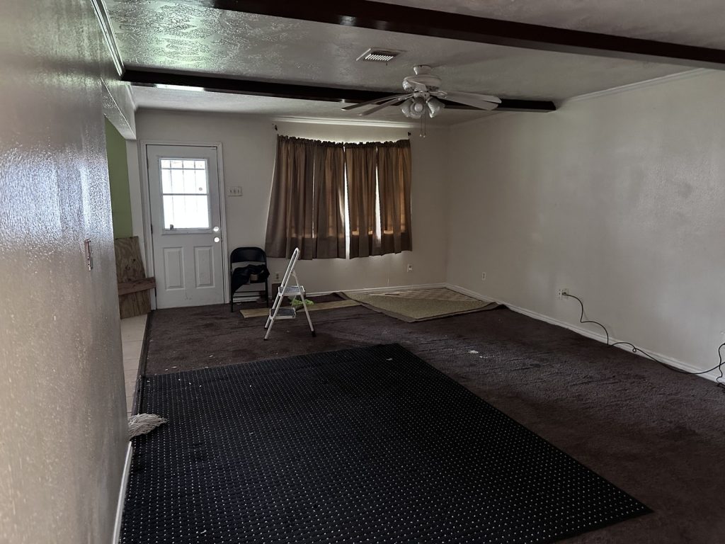 Empty living room in an abandoned inherited home sold for cash in Woodgate, Houston, TX