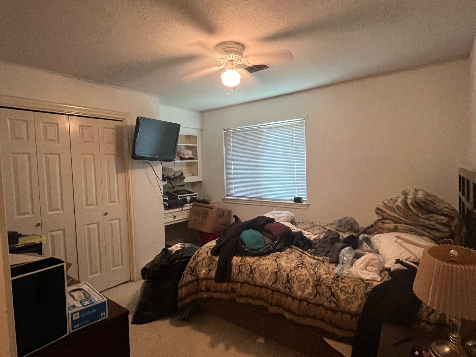 Bedroom mid-move inside a retiree's downsizing sale in Inwood North, Houston TX