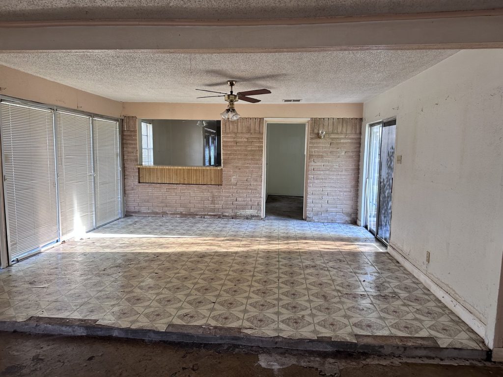 Open dining and living area in a vandalized home sold for cash in High Meadows, Aldine, TX