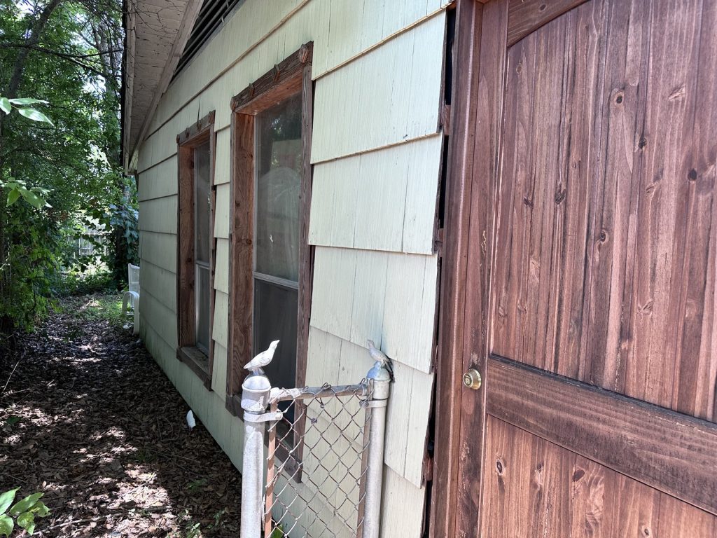 Damaged siding and exposed sheathing on estate property sold for cash in Houston TX