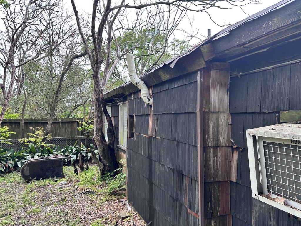 Rotted cedar shake siding on distressed Houston TX property purchased as-is