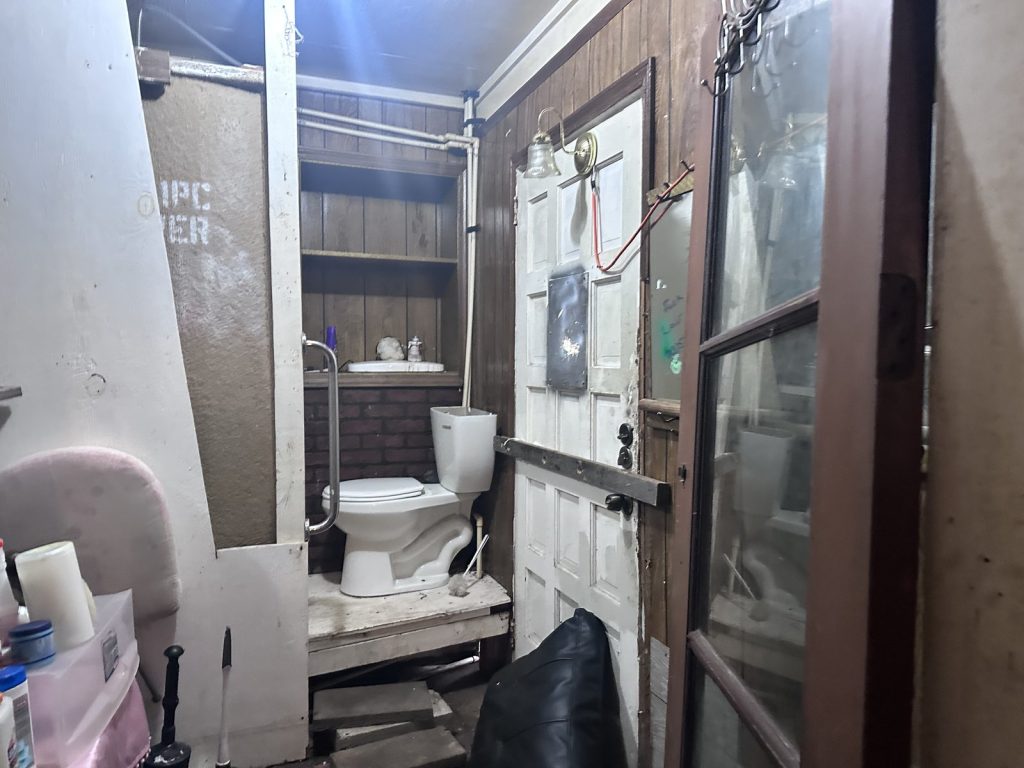 Damaged bathroom door and structural wear in a hoarder property purchased for cash in Greenwood Village, Houston, TX