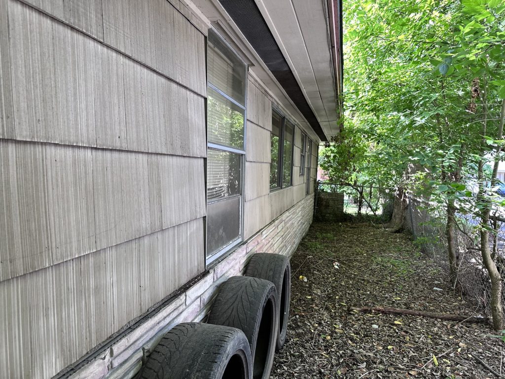 Side yard with stacked debris at vacant Crestmont Houston TX home sold as-is
