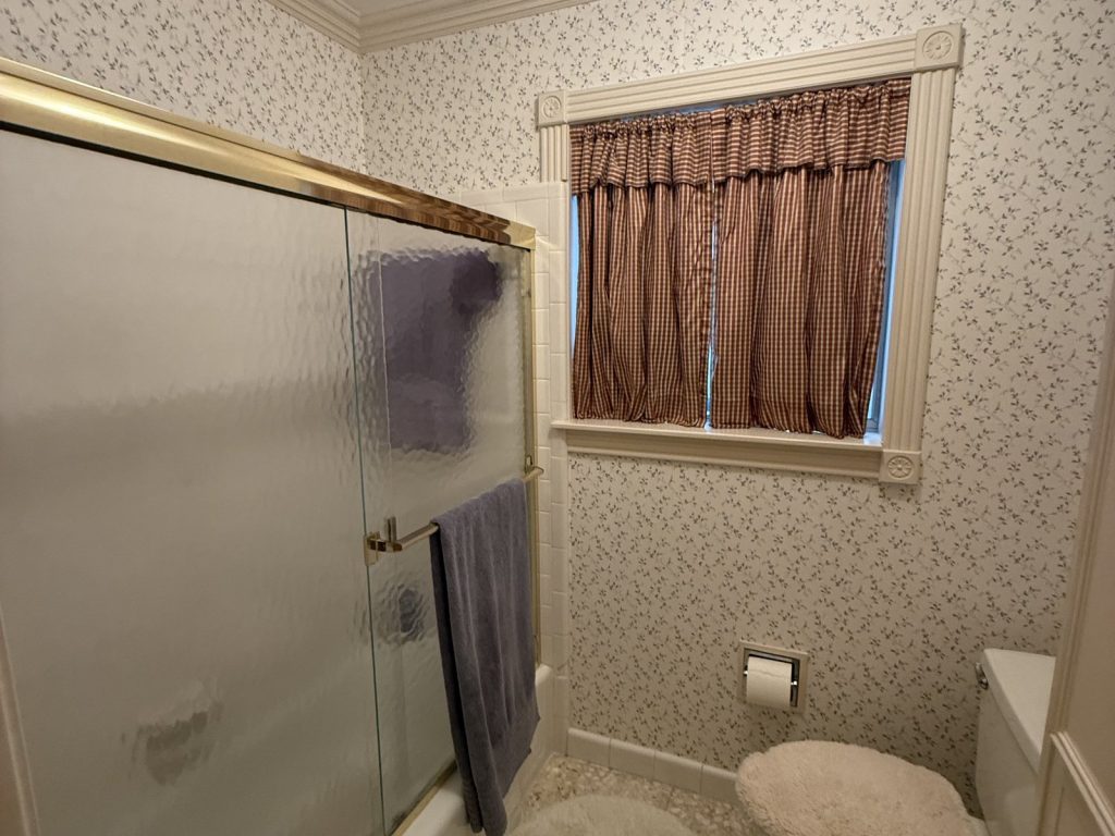 Dated wallpapered bathroom in Houston TX home purchased as-is with a leaseback