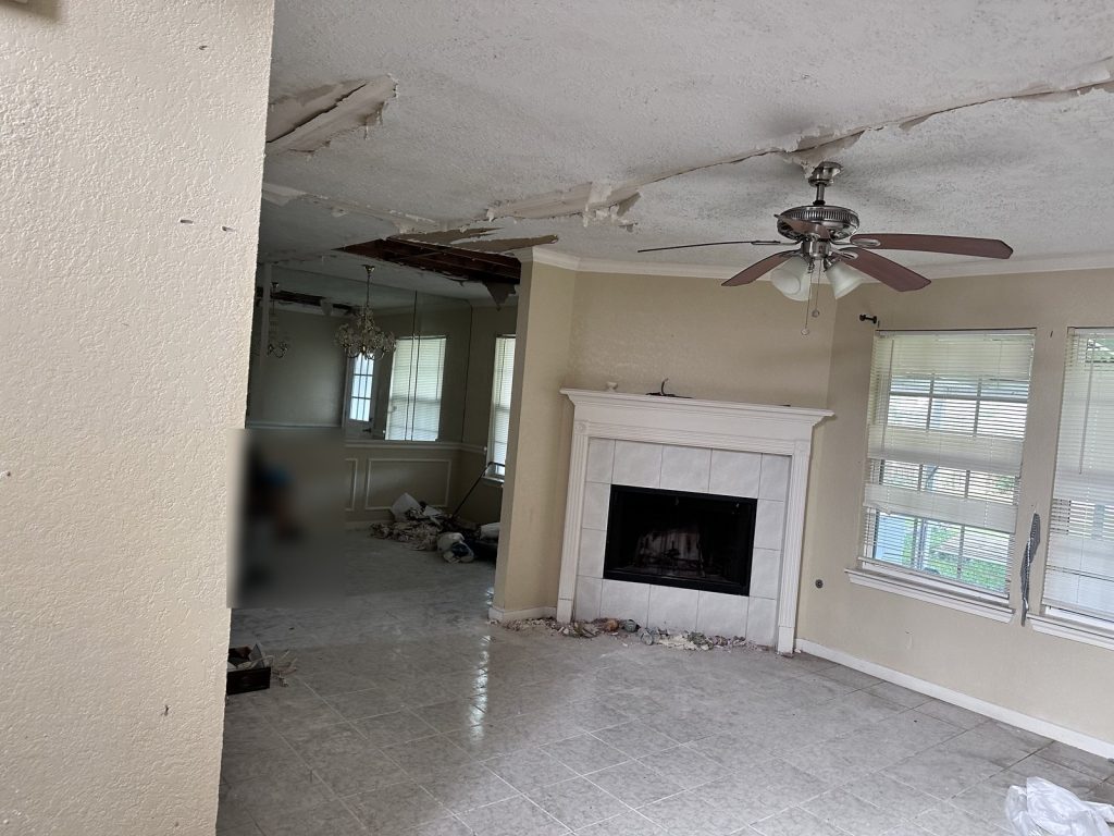 Living room with fire-damaged ceiling in a vacant home purchased for cash in Houston, TX