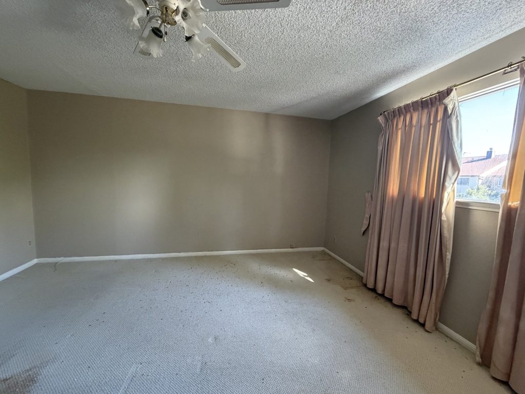 Empty bedroom with stained carpet in a long-vacant Spring Branch Houston TX home
