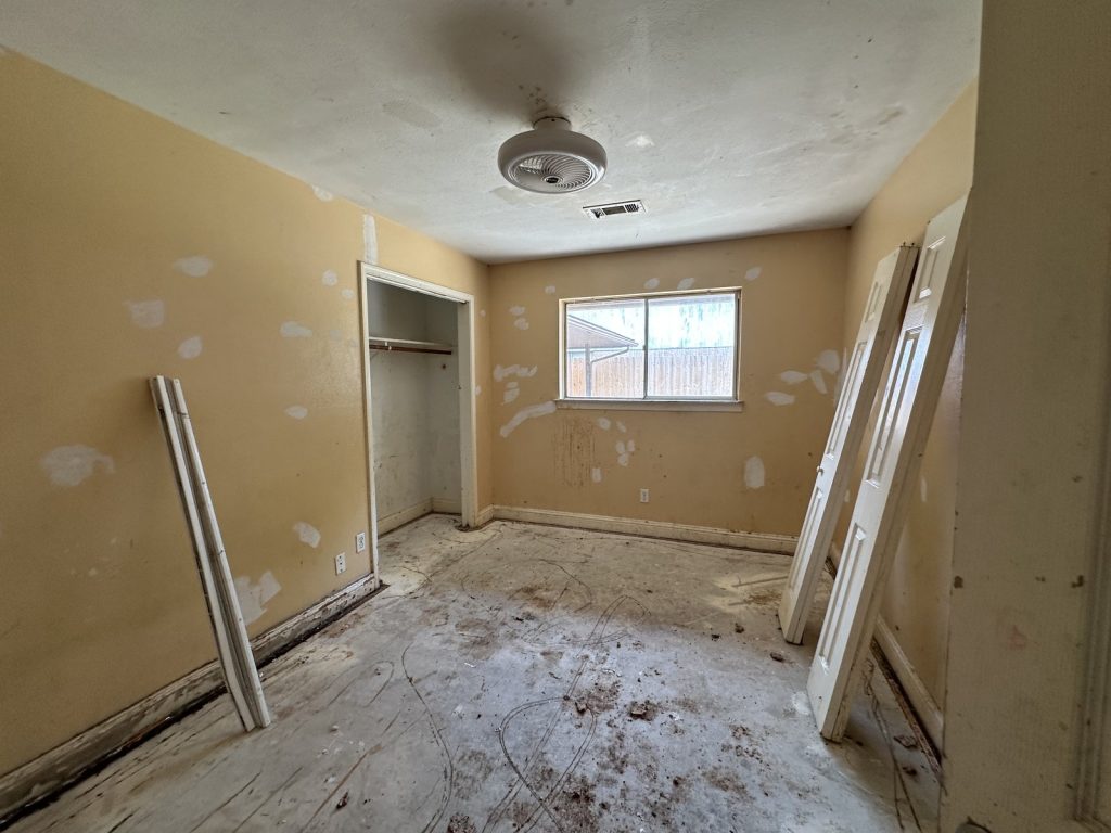 Gutted bedroom with bare slab in flood-damaged Houston TX property bought as-is