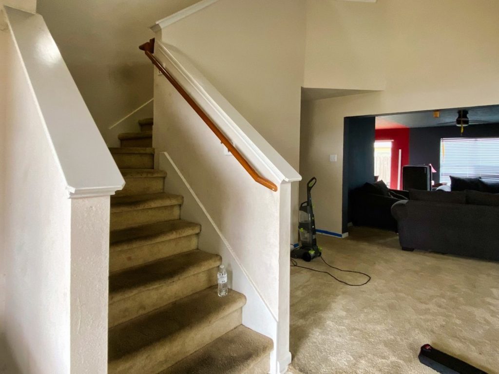 Open stairwell with worn carpet in Southbelt Houston TX rental sold for cash