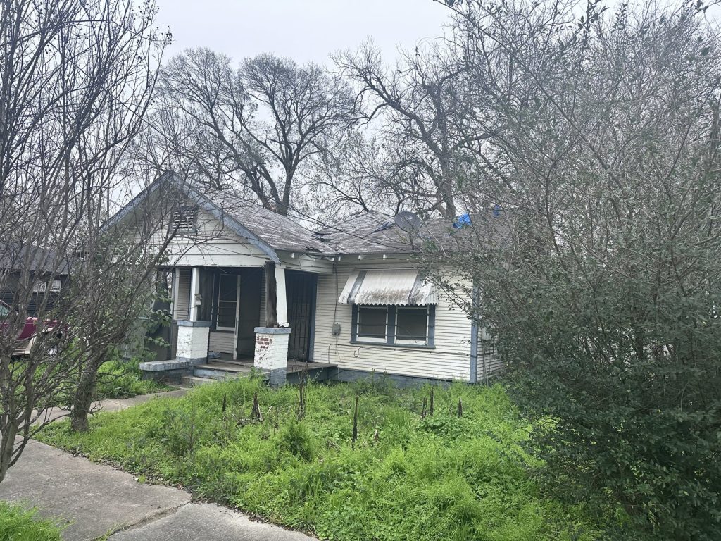 Overgrown front yard of long-vacant Clute TX property bought by cash home buyers