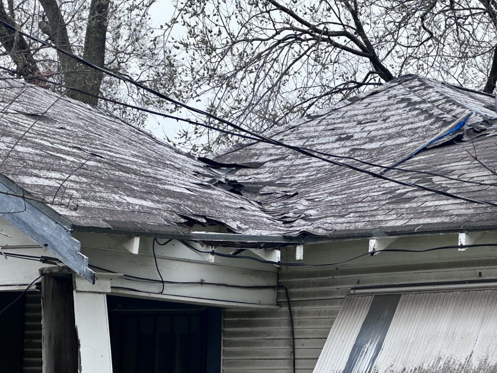 Failing roof with torn and lifted shingles on as-is Clute TX home purchased for cash