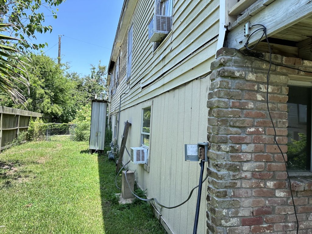 Side elevation and brick piers of flood-damaged home bought for cash in Galveston, TX