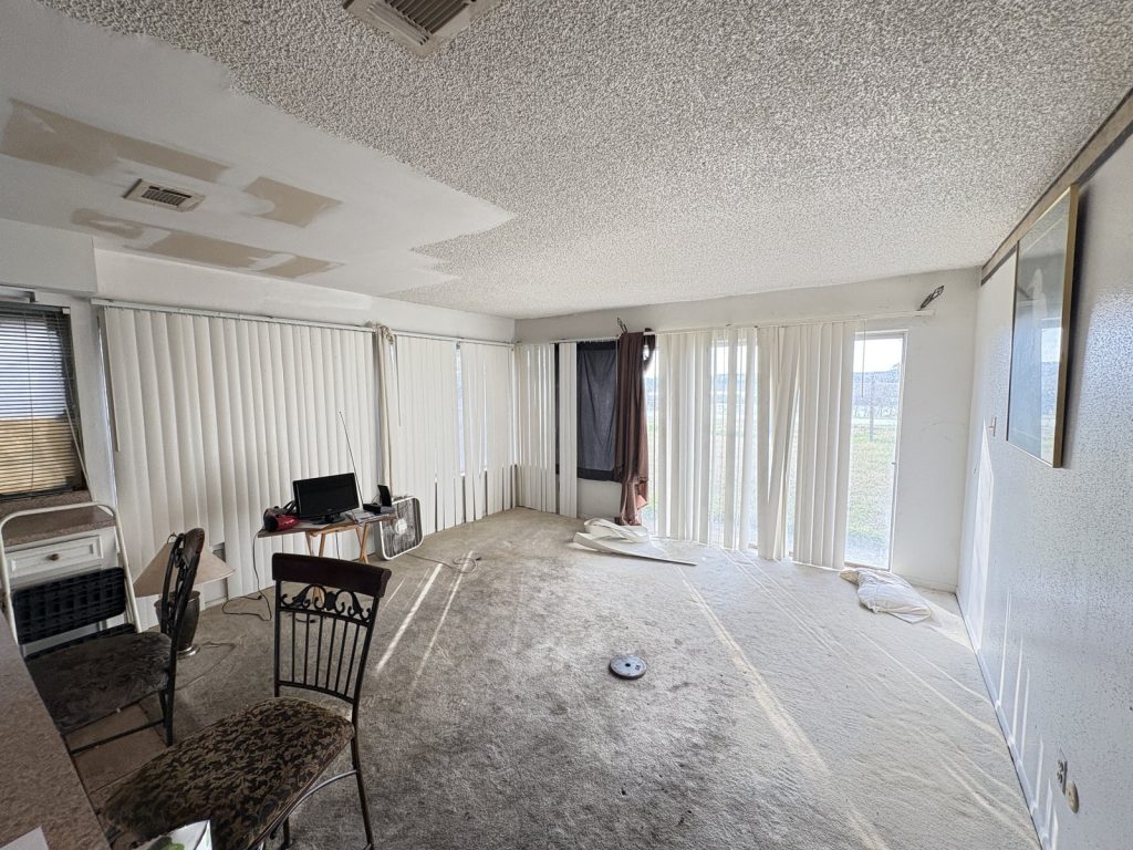 Den with damaged ceiling and stained carpet in as-is Houston TX house sold for cash