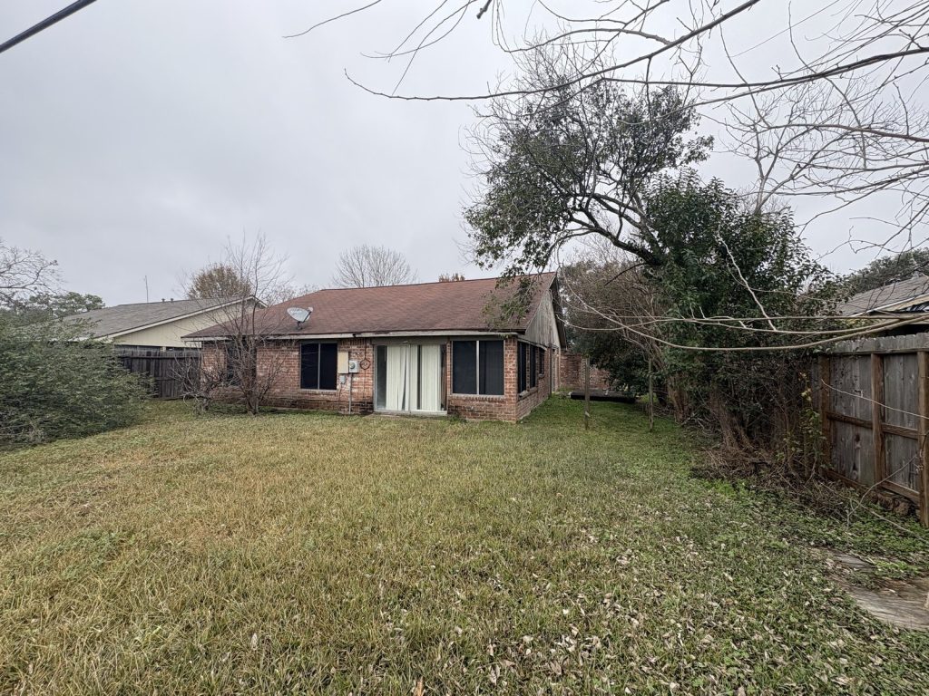 Overgrown rear yard of abandoned Woodland Trails Houston TX house sold as-is